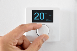 Una persona ajustando el termostato a 20 grados en un panel de control